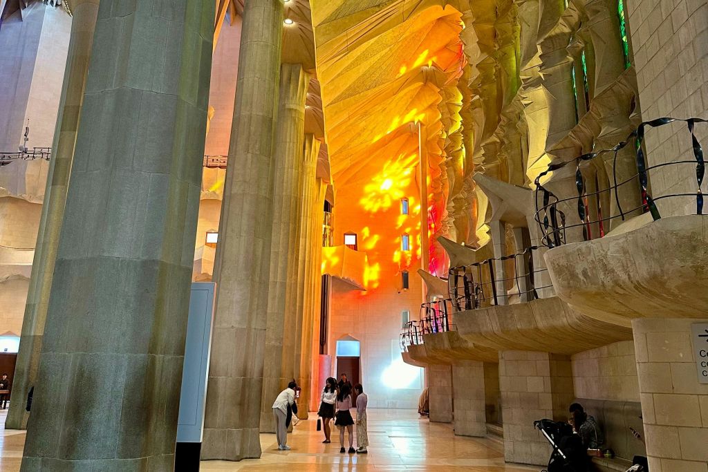 화려한 스테인드글라스 창문이 있는 대성당 내부의 사람들은 벽에 활기찬 빛의 무늬를 시전합니다.