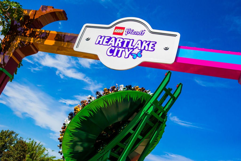 파란 하늘을 배경으로 롤러코스터 고리와 라이더가 있는 '레고 프렌즈 하트레이크 시티' 입구 표지판.