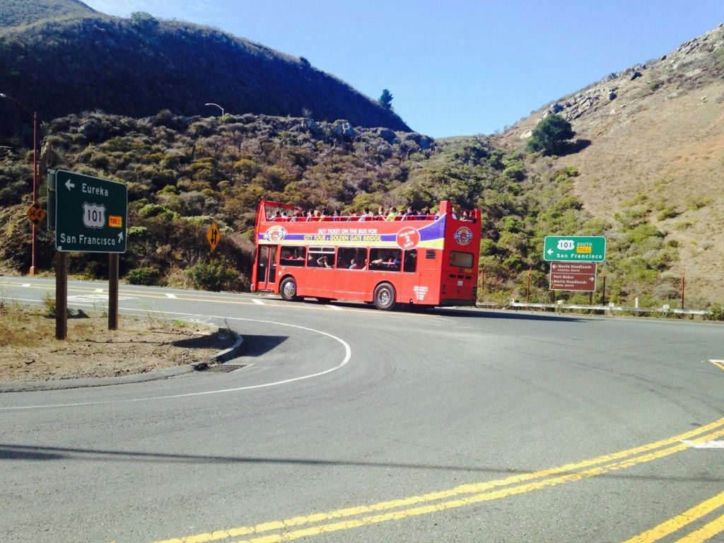101번 고속도로 표지판과 샌프란시스코와 유레카로 가는 길 근처의 산악 도로에서 빨간색 2층 투어 버스를 타세요.