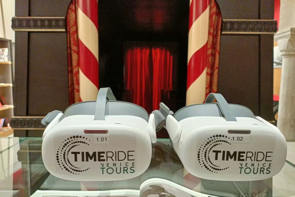반사 표면에 'TimeRide Venice Tours' 라는 라벨이 붙은 두 개의 가상 현실 헤드셋으로, 극장 같은 배경을 갖추고 있습니다.