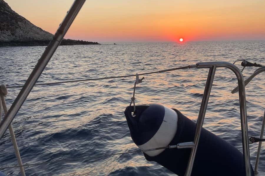 고요한 바다를 배경으로 석양을 배경으로 요트 난간과 파란색과 흰색 펜더가 있습니다.