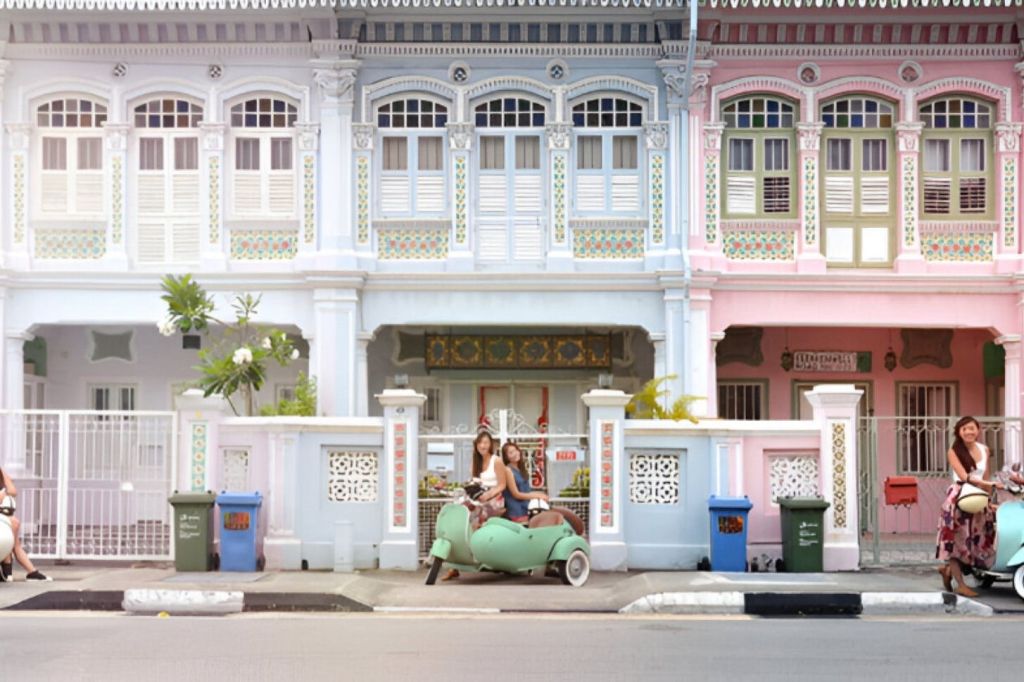 화려한 디테일이 돋보이는 화려한 전통 연립 주택 앞에 사이드카를 타고 초록색 전동 스쿠터에 앉아 있는 두 사람.