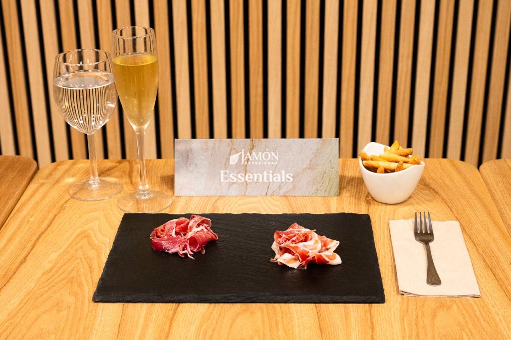 다진 고기 두 조각, 물 한 잔, 샴페인 한 잔, 감자 튀김 한 그릇을 담은 슬레이트 접시가 있는 테이블 세팅입니다.