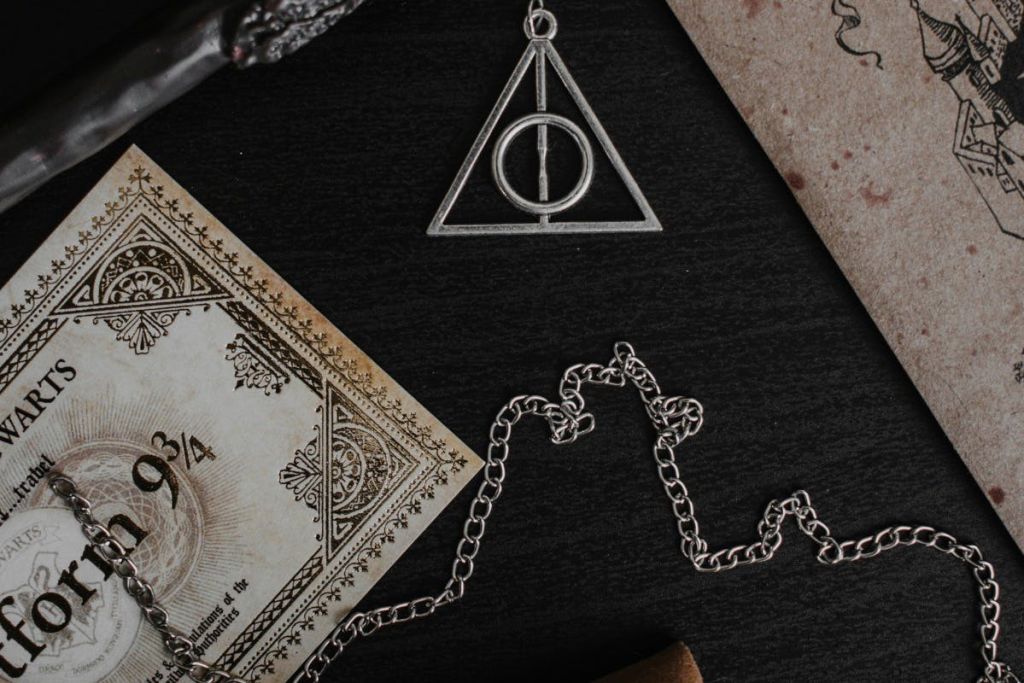 체인에 원과 선으로 디자인된 삼각형 펜던트로, 어두운 표면에 화려한 디자인의 빈티지 종이에 가깝습니다.