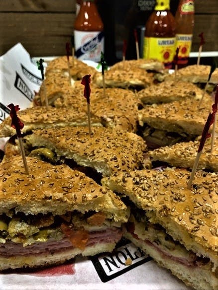 델리 고기, 야채, 양념이 가득한 참깨 샌드위치 슬라이스를 이쑤시개와 함께 클로즈업합니다.