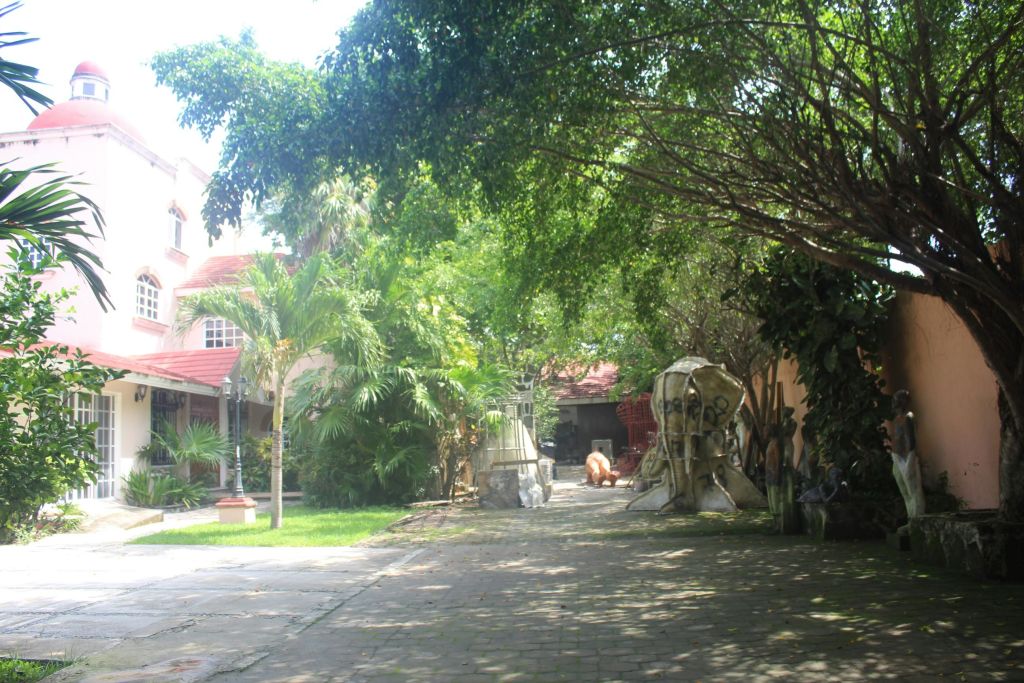 햇살이 내리쬐는 가로수가 늘어선 마당에는 조각품, 붉은 지붕의 건물, 울창한 녹지가 있습니다.