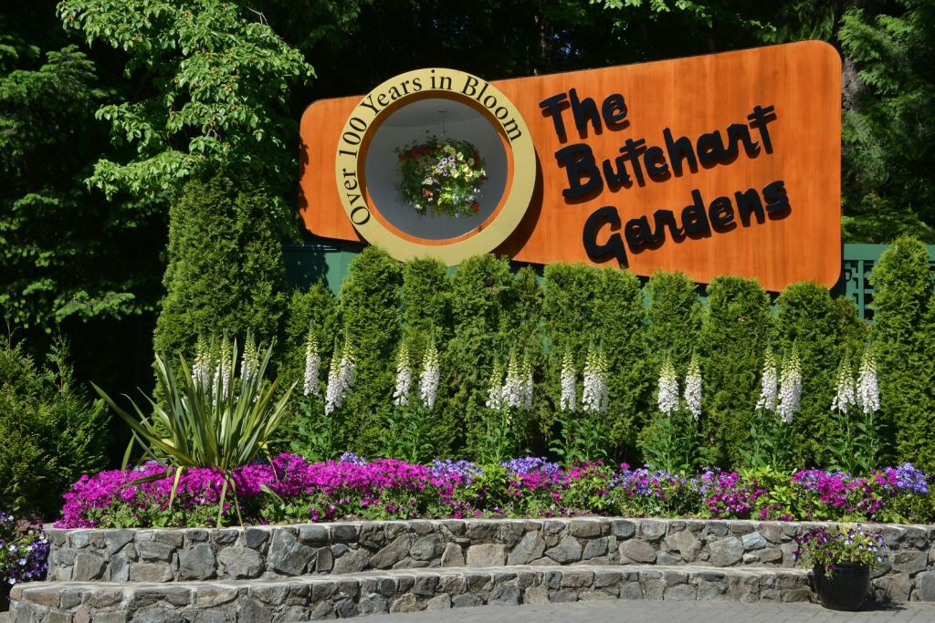 울창한 녹음과 화려한 꽃으로 둘러싸인 "The Butchart Gardens" 에 서명하세요. "100년 이상의 꽃" 이 원형 프레임으로 전시되어 있습니다.