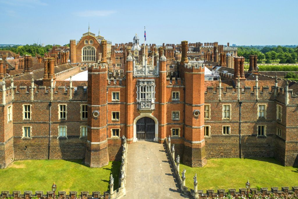 중앙 출입문이 있는 여러 개의 굴뚝과 타워가 있는 크고 유서 깊은 벽돌 건물의 공중 전망.