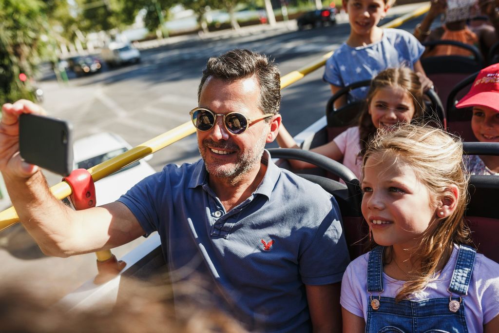 남자와 어린이가 야외 버스나 트램에 앉아 화창한 날 웃으며 라이딩을 즐깁니다.