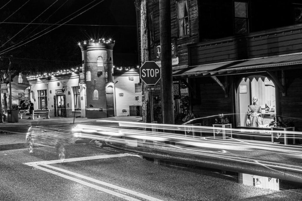 등산로, 건물, 정류장 표지판, 포탑이 있는 야간 거리의 흑백 사진.