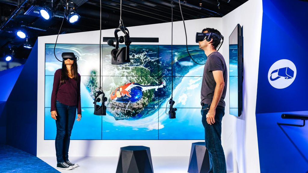 VR 장비로 둘러싸인 헬리콥터와 풍경의 항공 전망을 보여주는 대형 스크린 앞에 VR 헤드셋을 착용한 사람.