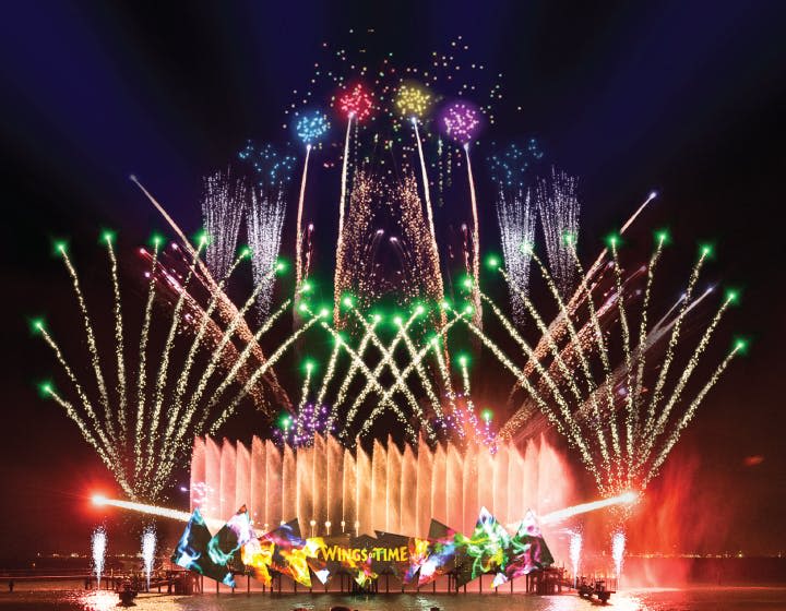 화려한 분수와 무대에서 '시간의 날개' 라는 글자가 빛나는 야외 야간 조명과 불꽃놀이가 펼쳐집니다.