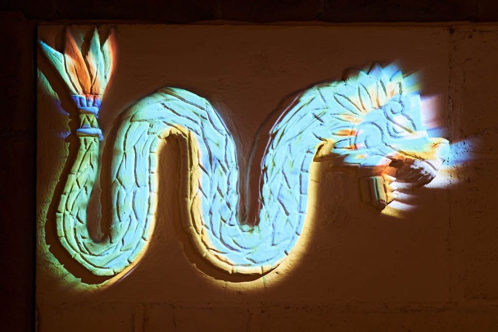 정교한 패턴과 선명한 블루, 옐로우, 오렌지 색상의 화려한 깃털 뱀 장식 벽 예술.