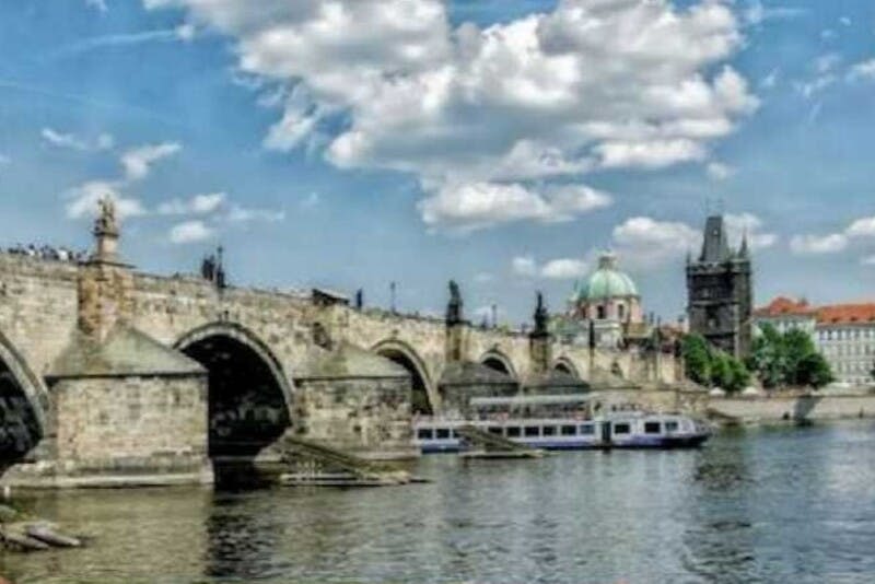 아치가 있는 석조 다리가 강에 걸쳐 있고, 그 아래에는 보트가 떠 있으며, 배경에는 돔형 건물이 보입니다.