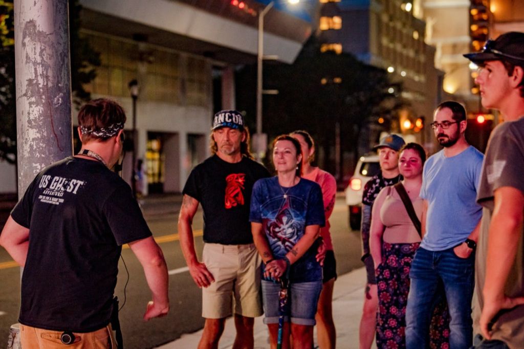 가로등과 건물을 배경으로 도심 속에서 한 무리의 사람들이 밤에 야외에서 함께 서 있습니다.