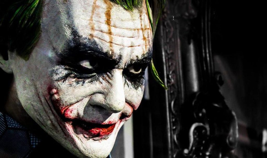 조커 캐릭터를 닮은 검은색 아이 메이크업과 붉은 입술로 하얀 얼굴 페인트를 칠한 사람의 클로즈업.