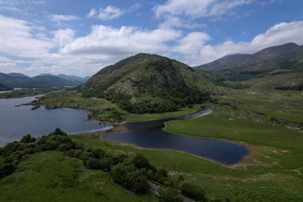언덕, 호수, 부분적으로 흐린 푸른 하늘이 있는 잔디밭의 경치.