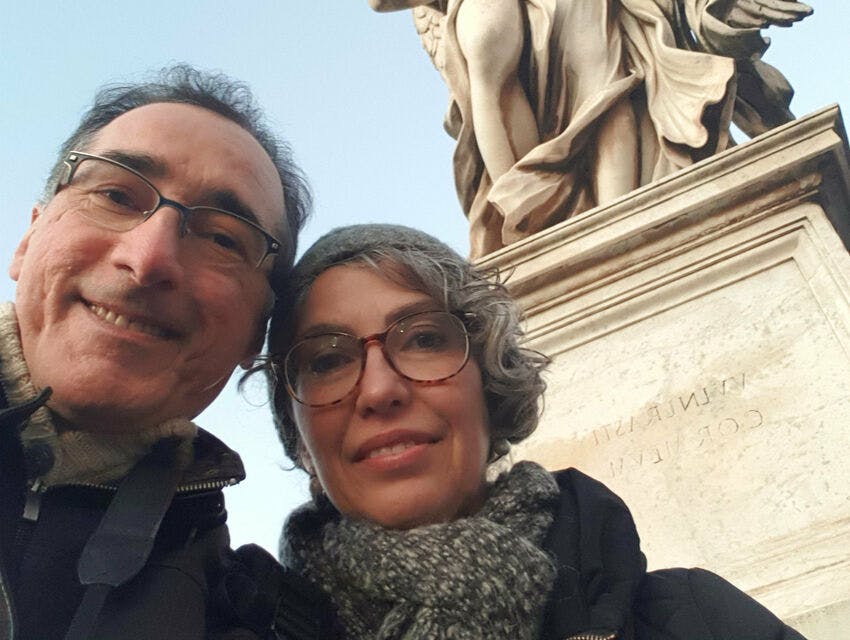 안경을 쓴 두 사람이 돌 조각상 앞에서 셀카를 찍는 포즈를 취하고 있습니다.