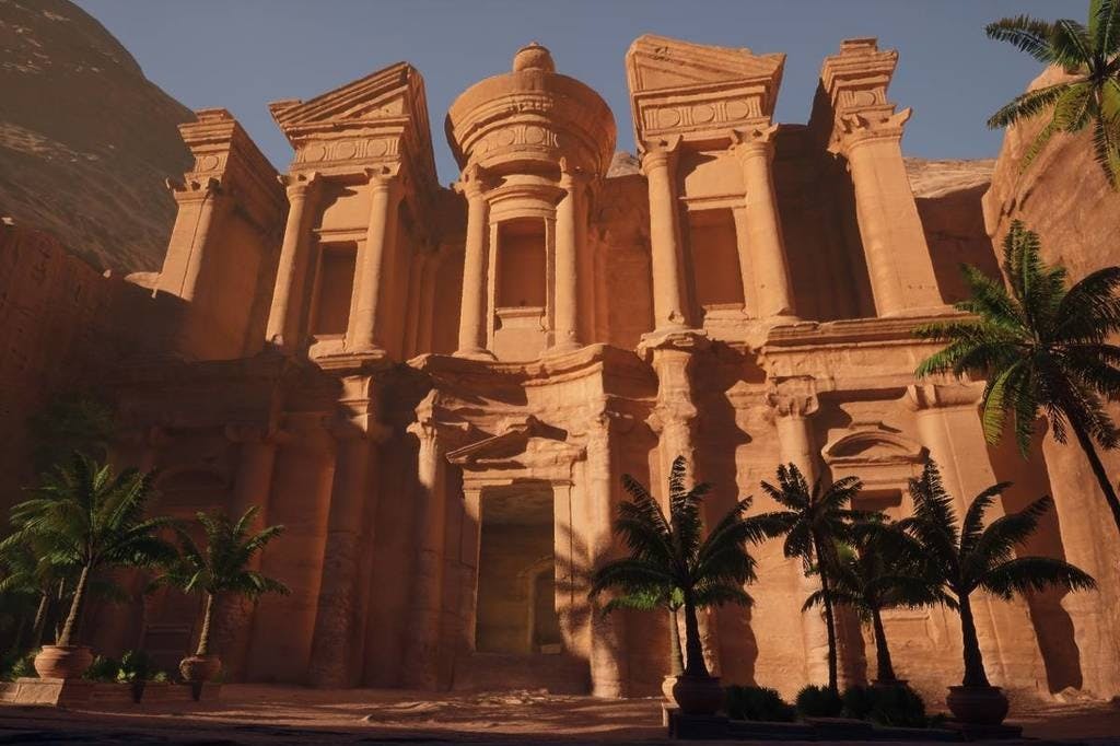 정교한 기둥과 조각이 있는 고대 석조 건물로, 맑은 하늘 아래 야자수 두 그루가 나란히 있습니다.