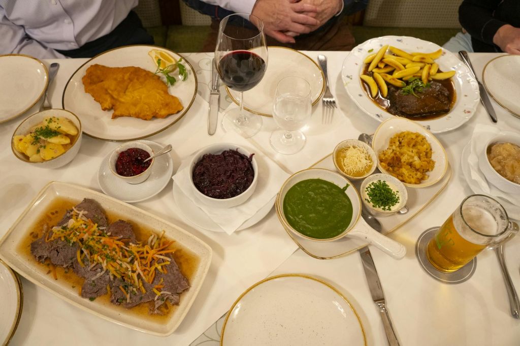 슈니첼, 야채, 소스, 와인 한 잔, 물 한 잔 등 다양한 요리가 놓인 테이블로, 2명이 앉을 수 있습니다.