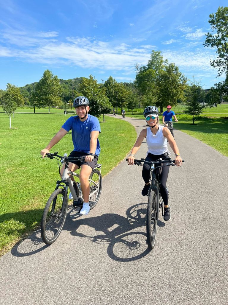 푸른 하늘 아래 푸른 공원의 포장도로에서 자전거를 타는 사람들.