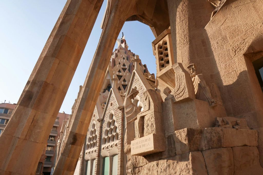 맑고 푸른 하늘 아래 기하학적 패턴과 뾰족한 아치가 있는 화려한 석조 건축 디테일의 클로즈업.