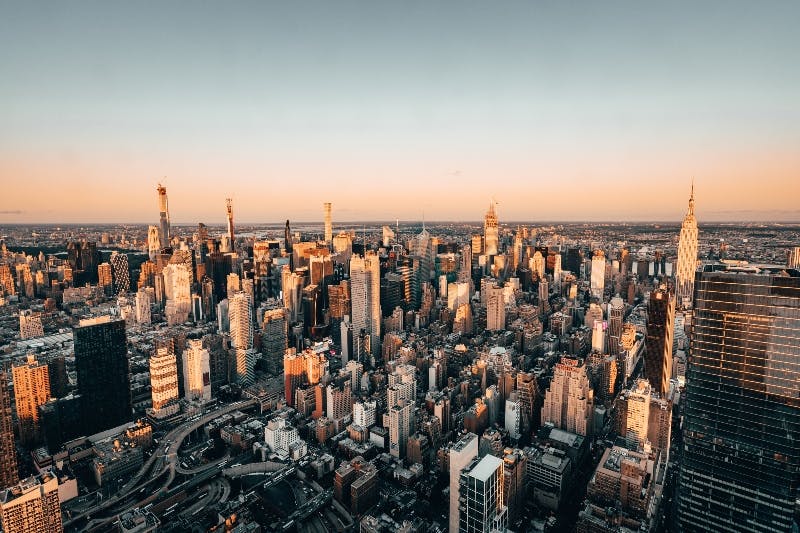 해가 질 무렵 맑은 하늘 아래 높은 건물이 있는 도시의 빽빽한 스카이라인을 공중에서 감상할 수 있습니다.