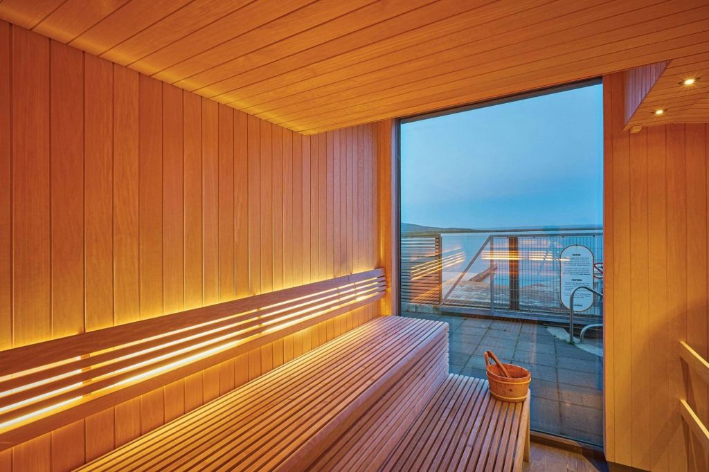 나무 벤치, 양동이, 커다란 창문이 있는 나무 패널 사우나 룸으로 발코니가 내려다보이며 새벽에는 먼 바다 전망을 감상할 수 있습니다.