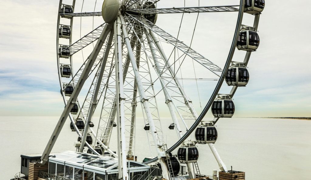 아래에서 바라보는 바다 옆의 동봉된 통나무집이 있는 대관람차.