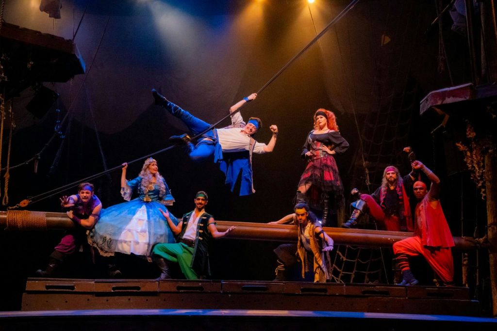 다채로운 의상을 입은 공연자들은 배처럼 디자인된 무대에서 리깅과 드라마틱한 조명으로 공연합니다.
