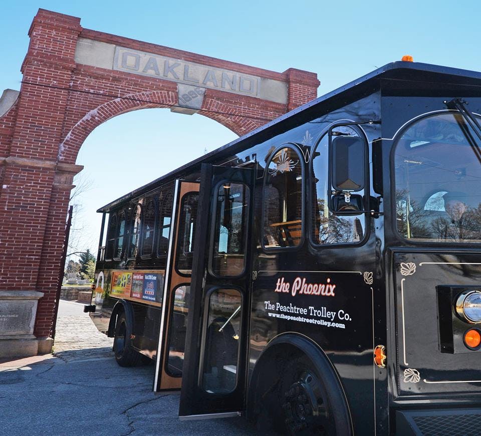 붉은 벽돌로 된 아치형 통로 앞에 '오클랜드' 라는 단어가 적힌 '피닉스' 라고 적힌 검은색 트롤리가 있습니다.