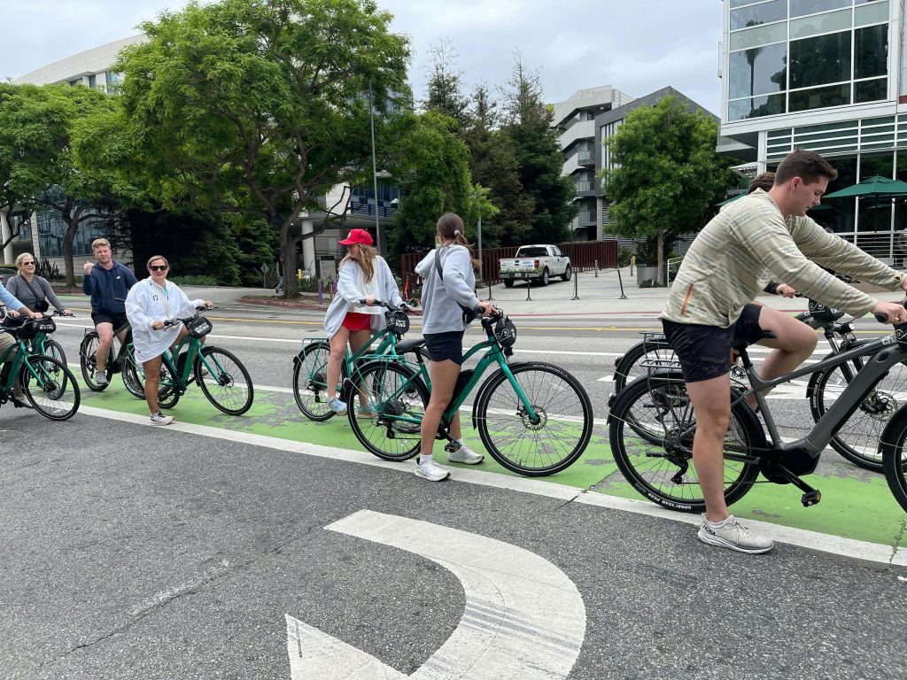 녹색 자전거 도로, 나무, 건물을 배경으로 한 도시 거리에서 녹색 자전거를 타는 사람들이 모여듭니다.