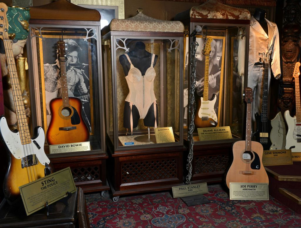 기타와 의상이 포함된 케이스를 David Bowie, Duane Allman, Paul Stanley, Joe Perry의 이름패와 함께 전시합니다.