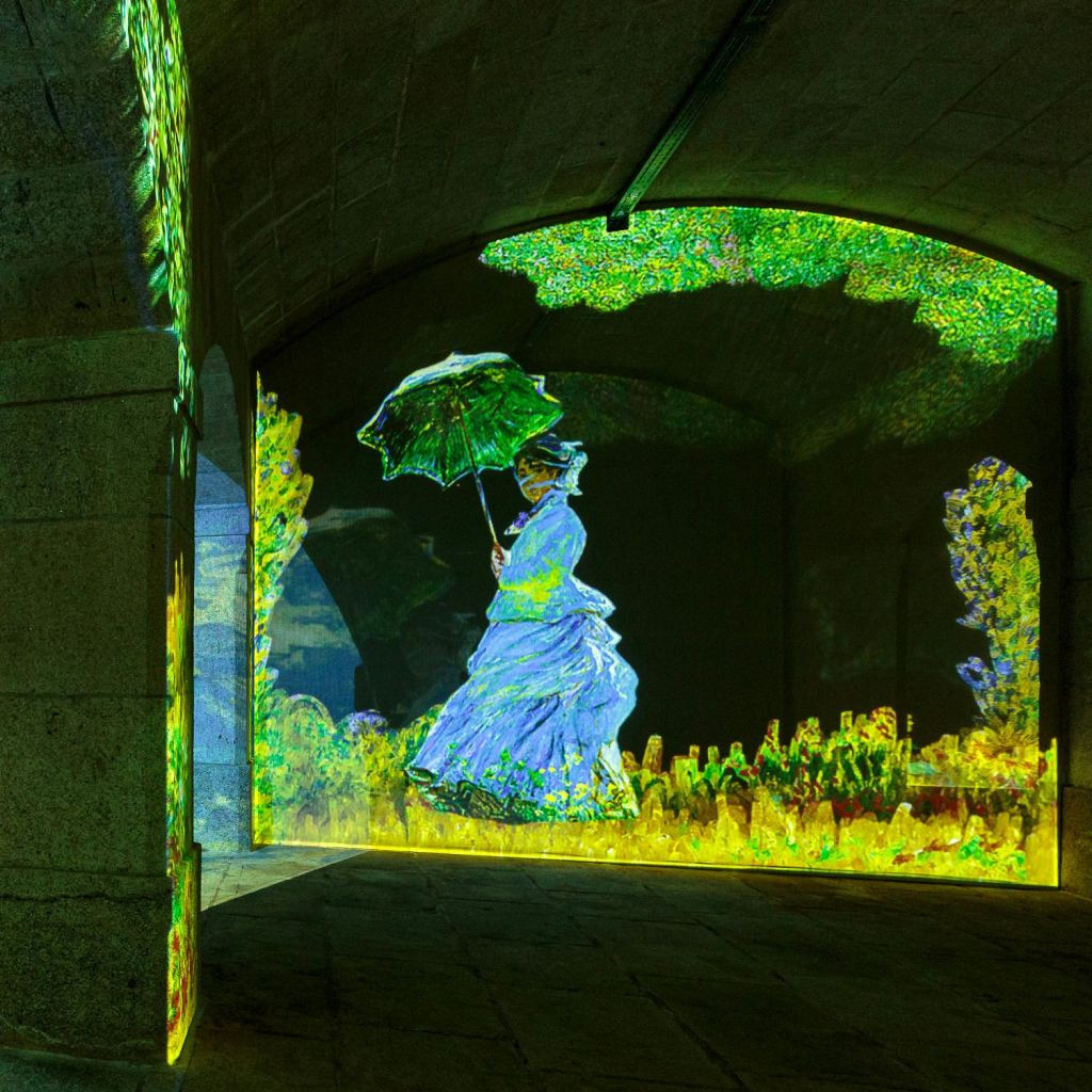 어두운 방 벽에 표시된 생생하고 화려한 배경에 파라솔을 들고 있는 여성의 디지털 투영.