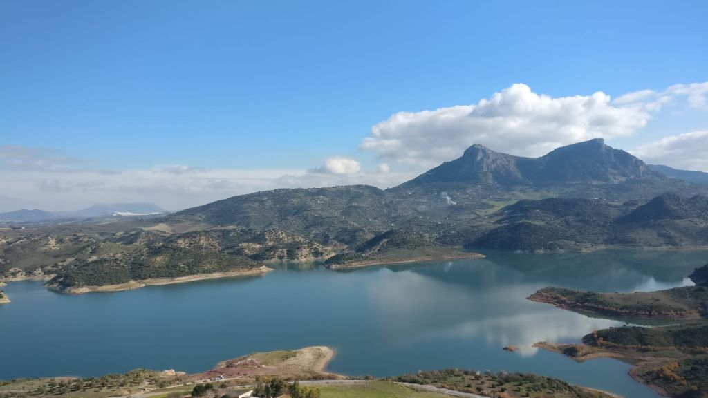 구불구불한 언덕으로 둘러싸인 고요한 호수와 구름이 흩날리는 맑고 푸른 하늘 아래 산.