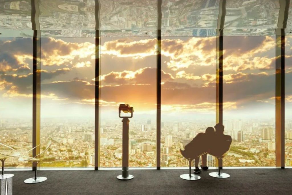 두 사람이 커다란 창가 의자에 앉아 도시의 풍경을 바라보며 일몰을 감상하고 있습니다. 양안 스탠드가 전면에 있습니다.