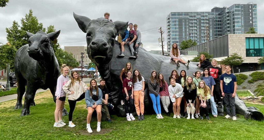 한 무리의 사람들이 야외 도심에서 황소 동상을 배경으로 포즈를 취하고 있습니다.