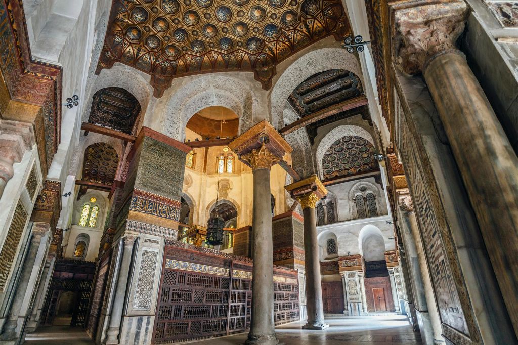 화려한 천장, 기둥, 아치형 개구부, 디테일한 벽 패턴이 있는 역사적인 건물의 정교하게 디자인된 내부.