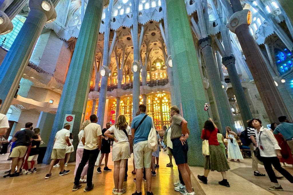 화려한 스테인드글라스 창문과 높고 화려한 기둥이 있는 커다란 대성당 안에 서 있는 사람들.