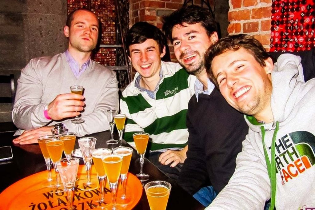 한 무리의 사람들이 바에서 술을 테스트하며 미소 짓고 있습니다.