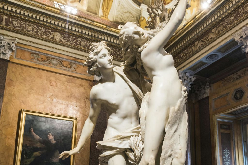 장식적인 디테일이 돋보이는 화려한 인테리어를 배경으로, 역동적인 포즈를 취한 두 인물을 묘사한 대리석 조각입니다.