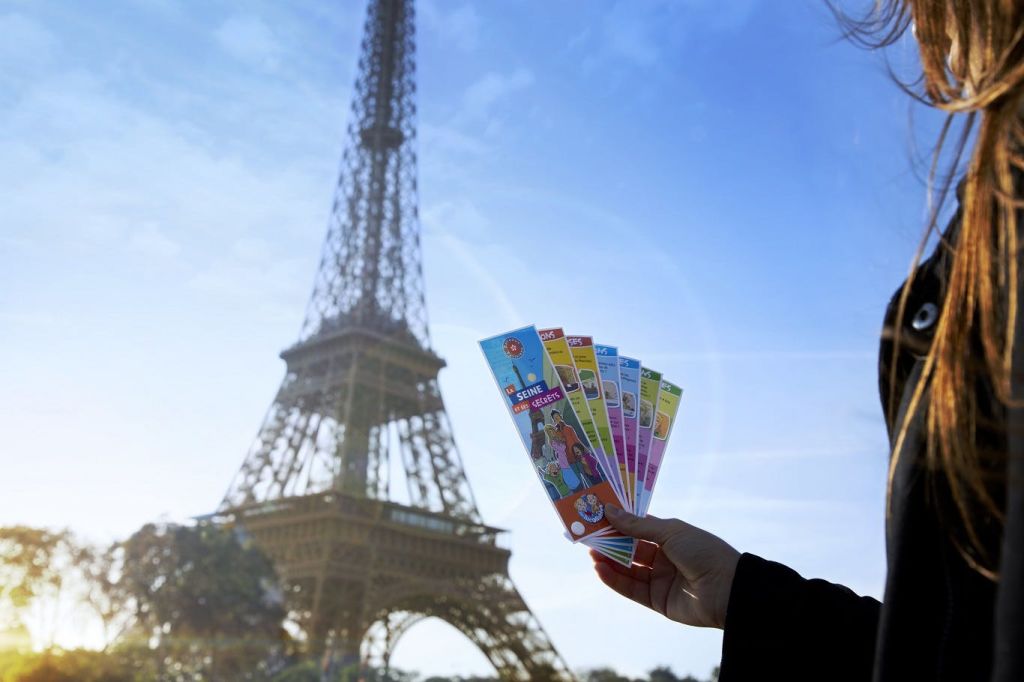 손에는 맑은 날 에펠탑 앞에서 만화 캐릭터가 그려진 다채로운 어트랙션 티켓이 있습니다.
