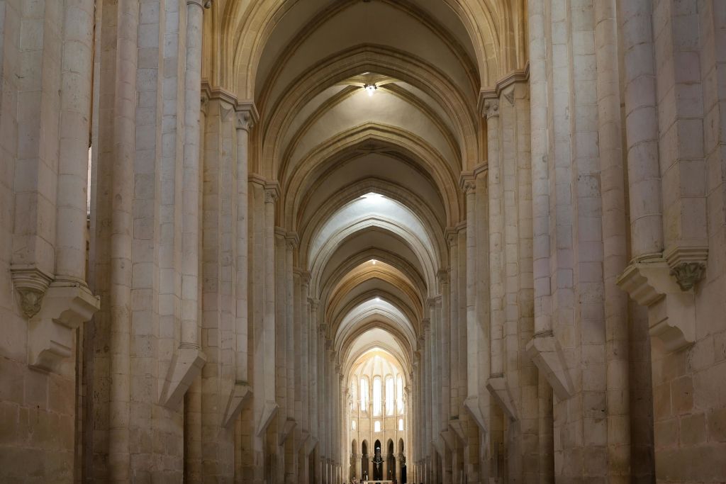 높고 뾰족한 아치와 밝은 빛이 맨 끝에 있는 창문을 통해 흐르는 대성당의 내부 전망.