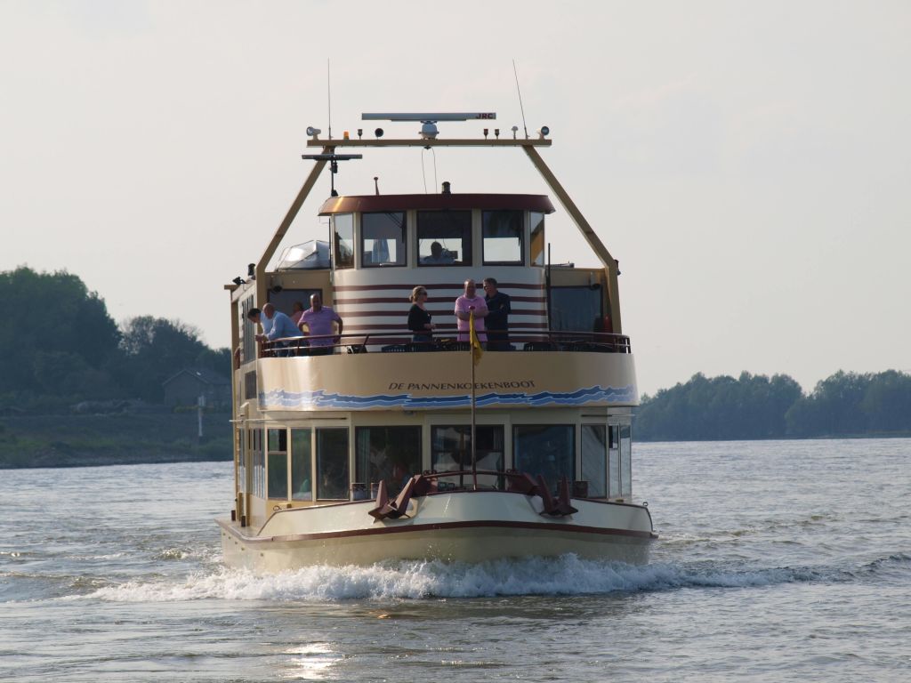 위층 갑판, 나무, 건물을 배경으로 사람들이 강가에 2단 보트를 타고 있습니다.