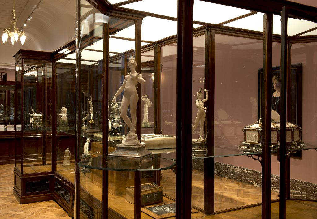 여러 클래식 스타일의 대리석 조각상을 전시한 유리 캐비닛이 전시된 박물관입니다.