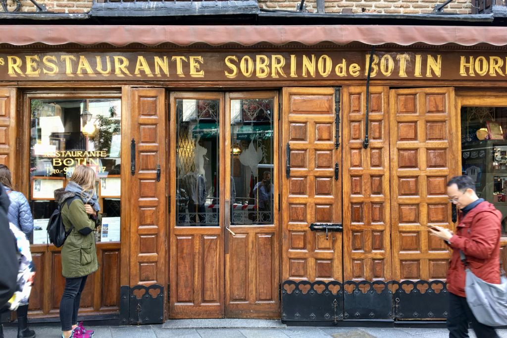 소브리노 데 보틴 (Restaurante Sobrino de Botín) 의 나무 외관에 유리 문이 있어 입구 근처에 서 있습니다.