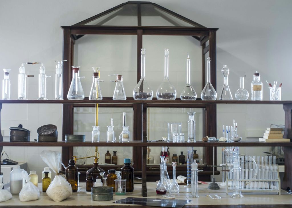 다양한 유리 비커, 플라스크, 병 및 기타 과학 장비로 채워진 실험실 선반.