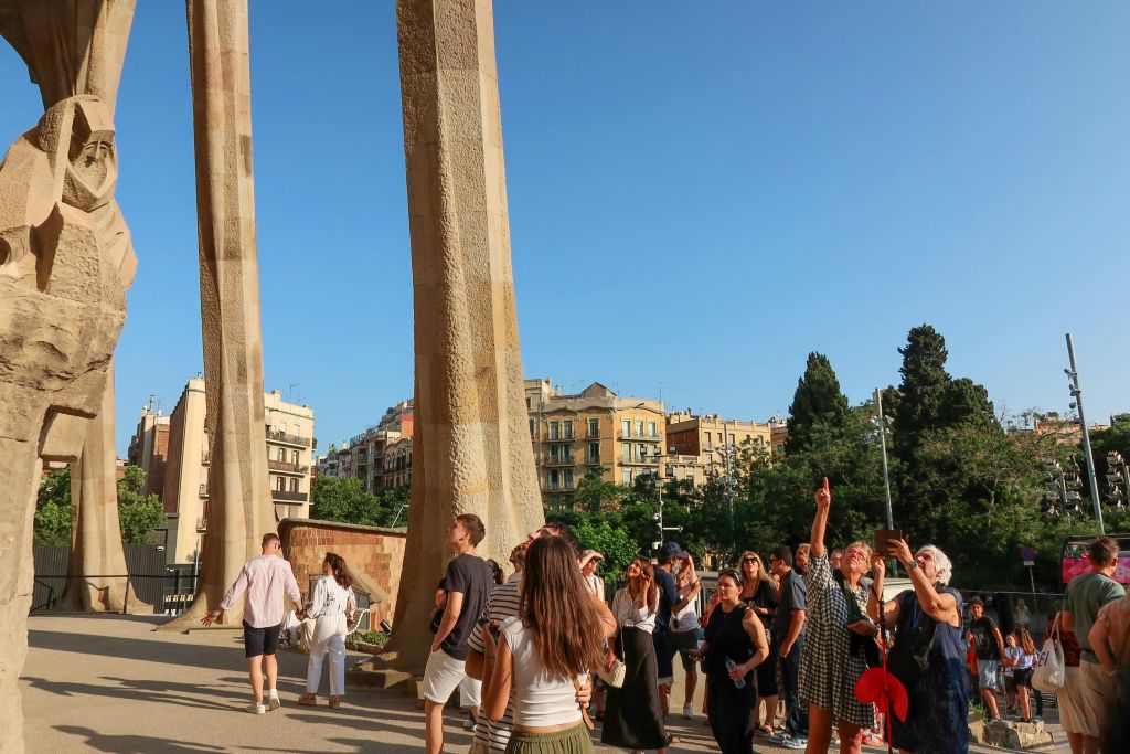 한 무리의 사람들이 도시 풍경을 배경으로 맑고 푸른 하늘을 배경으로 높은 돌기둥 근처에 모여들었다.