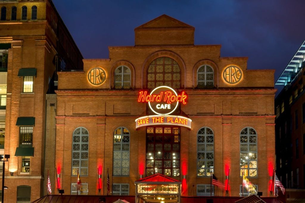 커다란 창문이 있는 벽돌 건물, 밤에 붉은 불빛이 비추는 '하드록 카페' 와 '세이브 더 플래닛' 이라는 네온 사인.