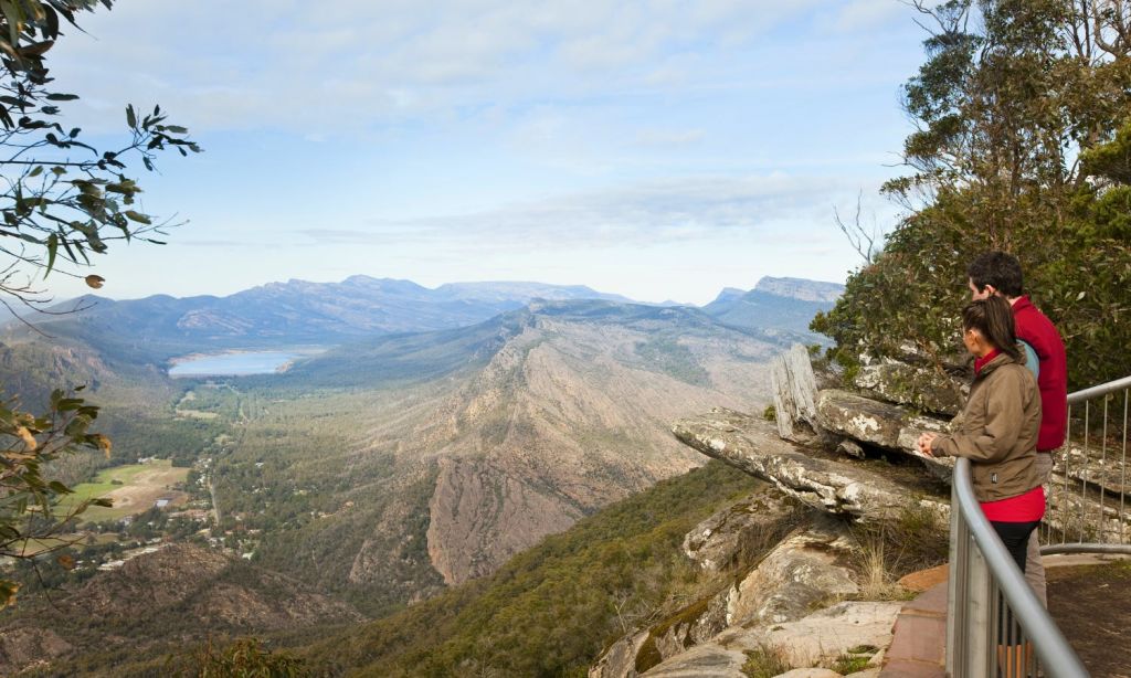 부분적으로 흐린 하늘 아래 먼 산이 있는 푸른 계곡이 내려다보이는 바위 절벽에서 바라보는 풍경.